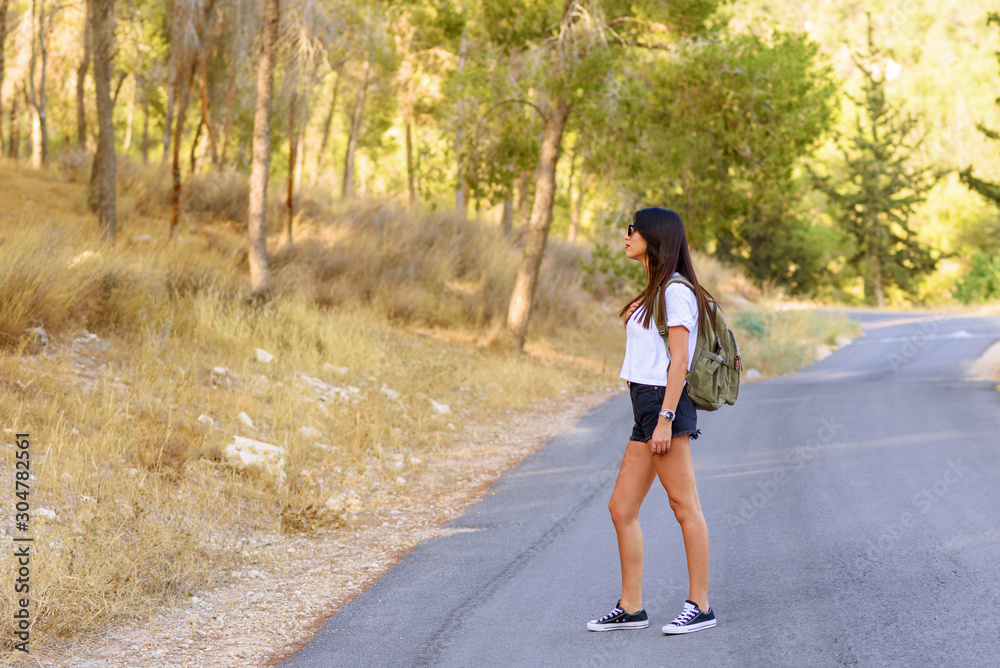 Concept of zero waste travel, healthy lifestyle. Happy young woman hiker with hemp backpack that has lots of room for plastic-free items standing on roads in the forest, admiring beautifull landscape. Concept of zero waste travel, healthy lifestyle. Happy young woman hiker with hemp backpack that has lots of room for plastic-free items standing on roads in the forest, admiring beautifull landscape.
