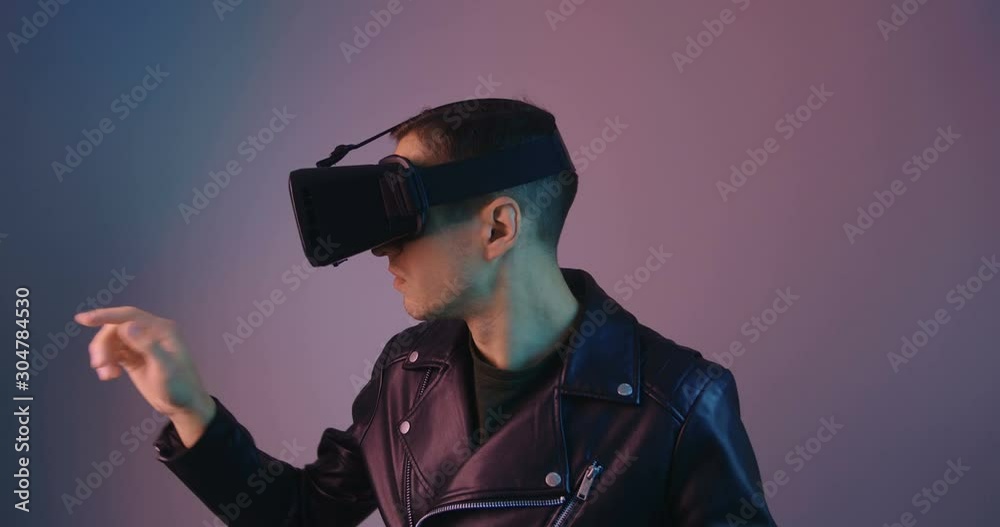 Close up of male using VR Glassess in multicolor neon light. Portrait of a young man in virtual reality helmet in futuristic neon lights. Close up of male using VR Glassess in multicolor neon light. Portrait of a young man in virtual reality helmet in futuristic neon lights.
