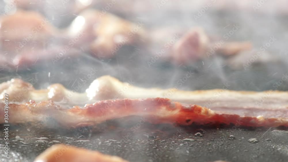 Bacon strips cooked on griddle in slow motion