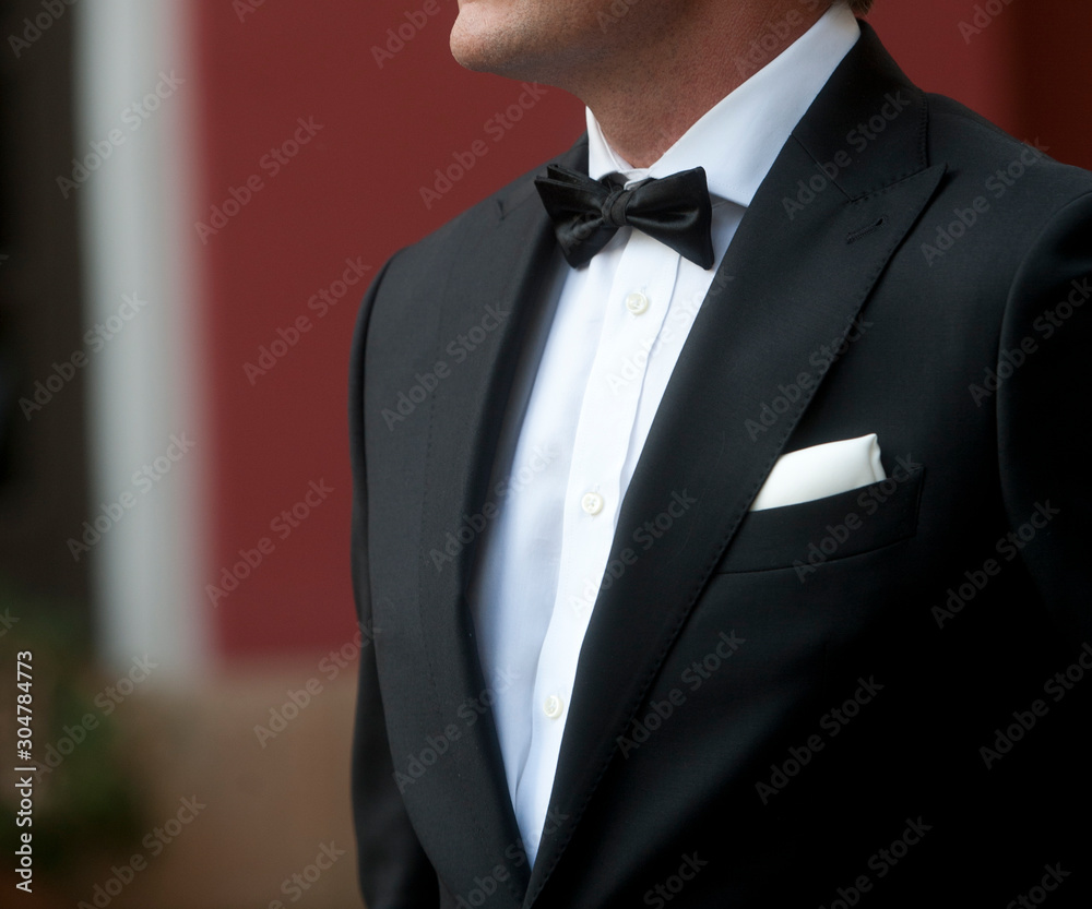 man with tuxedo in motion white shirt black bow tie black jacket and white  scarf background in green and terracotta colors Stock-Foto | Adobe Stock