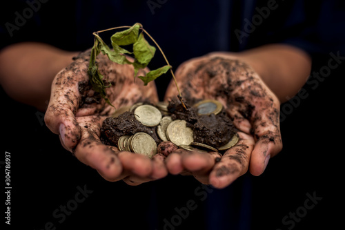 Close up of hands full mud with handful of coins in them. Found treasure. Holding gold and silver coins. photo
