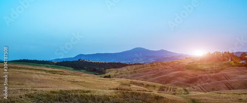 Tuscany, rural landscape. Rolling hills, countryside farm, cypresses trees, green field on warm sunset. Italy, Europe.