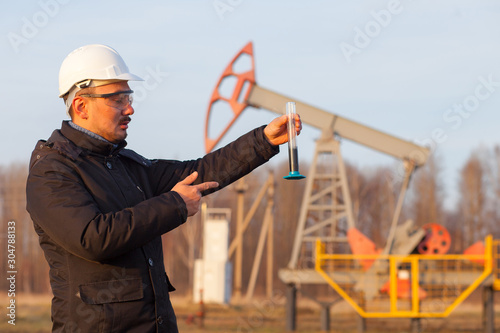 Engineer in a white helmet on an oil rig with a tablet. Oil production in Russia, Republic of Bashkortostan. Quality control. Oil production schedule