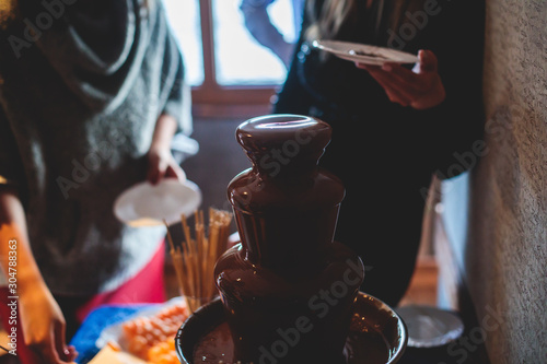Vibrant Picture of Chocolate Fountain Fontain on a children kids birthday party with a kids playing around and dipping marshmallows and fruits into the fountain