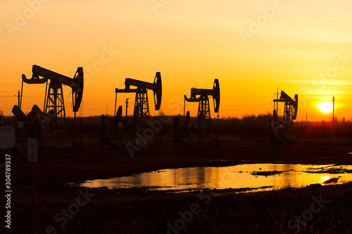 Working oil pump in rural place at sunset