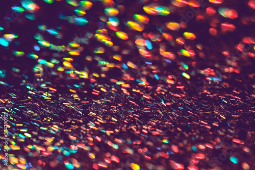 Multicolor blurred neon lights star flares and rainbow glitter on dark background. Bokeh lens flare glow. Festive backdrop with selective focus. Christmas New Year fireworks photo