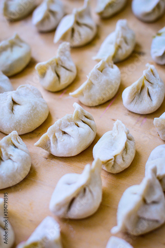 Close-up of Chinese Uncooked Dumplings Placed on Wood Surface. The Dumplings, called Jiaozi in Chinese, is a popular traditional Chinese food, especially during Chinese New Year.