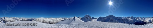 Panoramic view of snowy mountains peaks in the clouds blue sky Caucasus