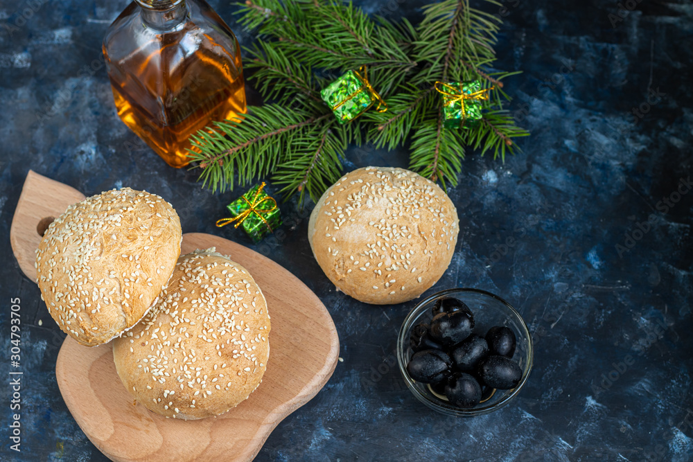 Baked hamburger buns. Sprinkled with sesame seeds. On a dark background. Copy space. Baked hamburger buns. Sprinkled with sesame seeds. On a dark background. Copy space.