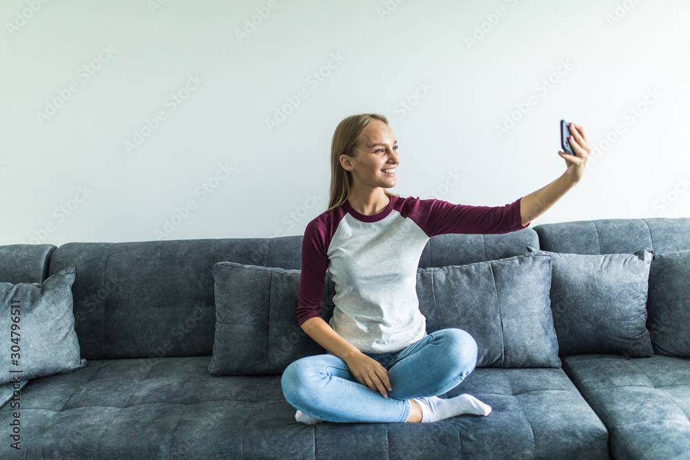 Beautiful pretty woman at home on the couch do selfie on cell phone Beautiful pretty woman at home on the couch do selfie on cell phone