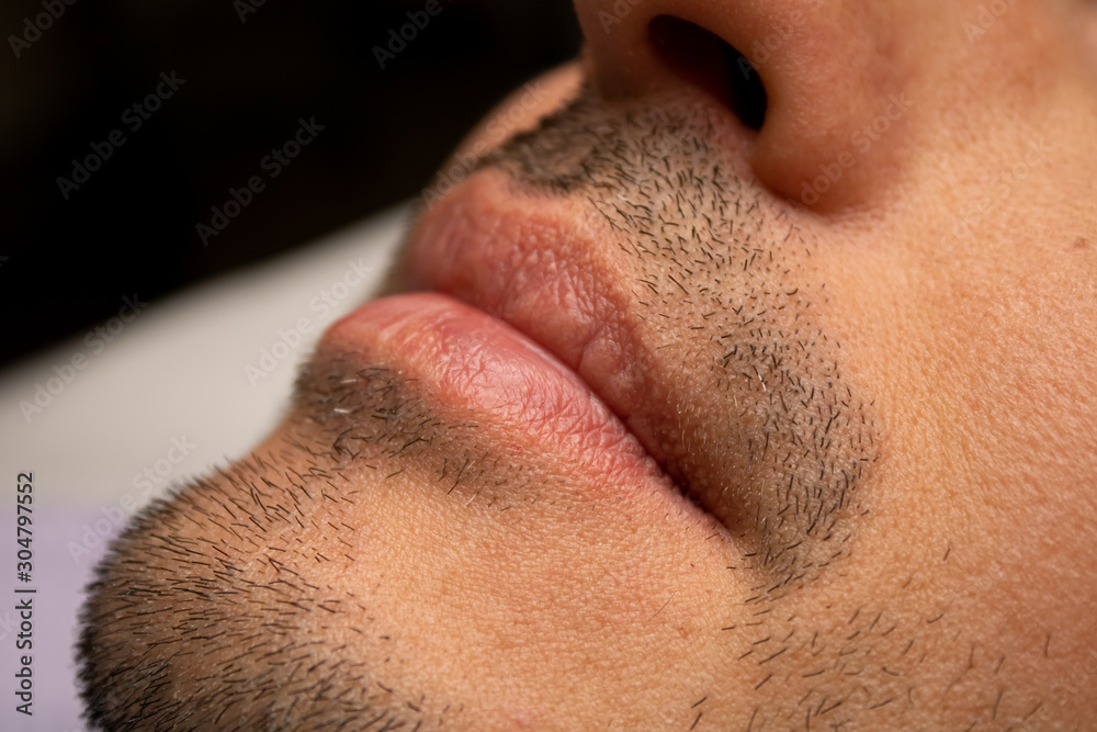Fototapeta premium Male NU Lips. Young man closeup lips, male permanent make up, men's bristle.
