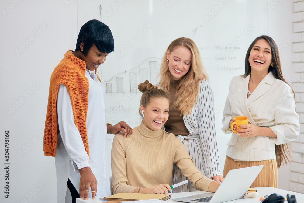 Obraz premium Multi-ethnic group of business female, african and caucasian women coworking in light modern executive office. Smile and enjoy work together
