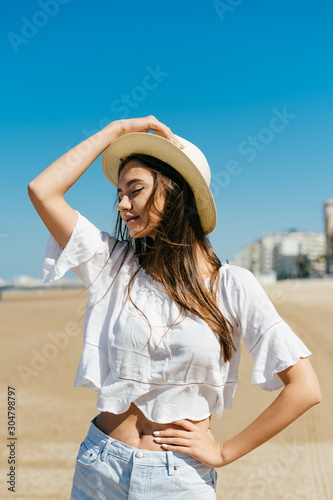 the girl in profile holds her hand on the hat, closed her eyes and with a smile of courage, she lifted her arms with her other hand © mnelen.com