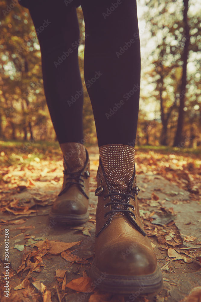 Women's legs standing in autumn leaves.