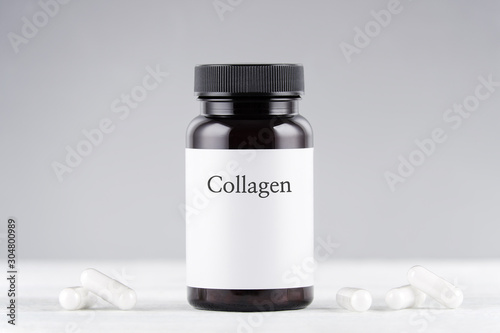 nutritional supplement collagen bottle and capsules on gray photo