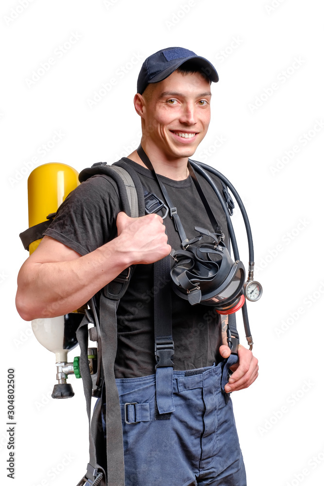 Young smiling firefighter with a mask and an air pack on his back in black t-shirt Young smiling firefighter with a mask and an air pack on his back in black t-shirt