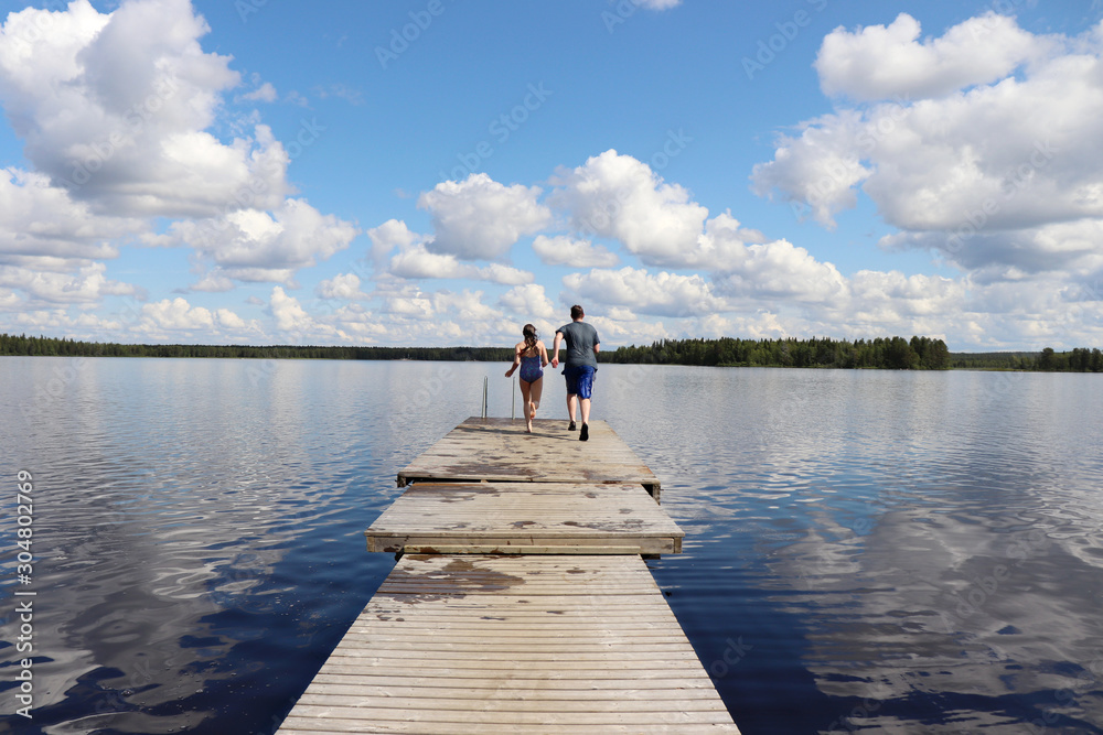 Teenagers running on a wooden pier at Lake Ranuanjarvi in Finland