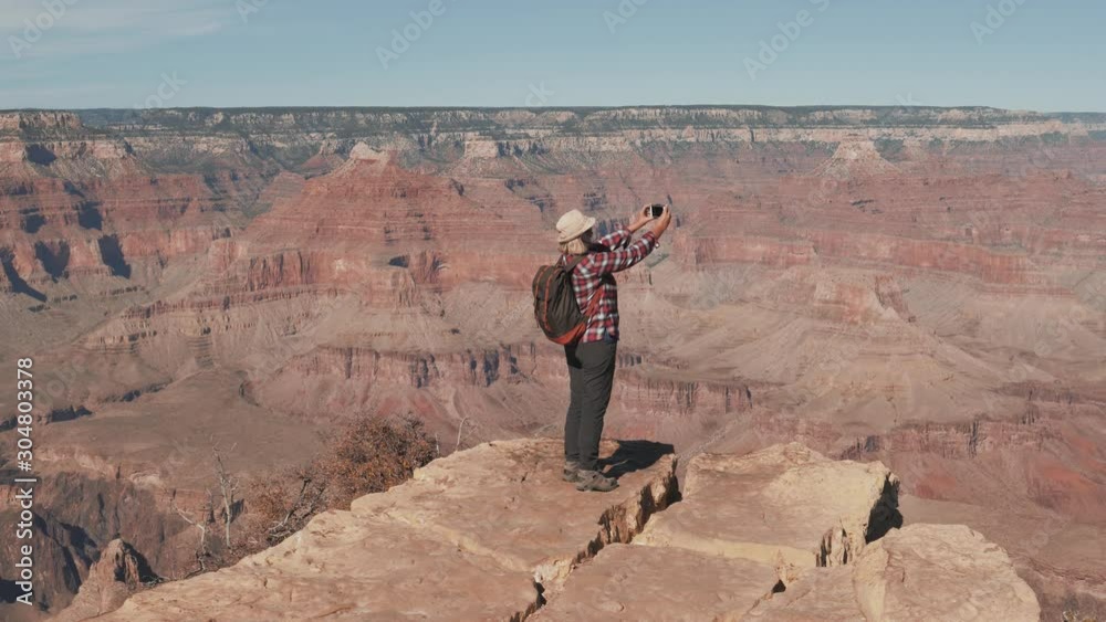 Hiker Woman Takes Photo On Smartphone Standing On Edge Of Rocks In Grand Canyon Hiker Woman Takes Photo On Smartphone Standing On Edge Of Rocks In Grand Canyon