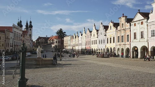 TELC, CZECH REPUBLIC - OCTOBER 12, 2019: Scenic view of main square of Telc with ancient houses and fountain with statue of Virgin overlooking bell towers of church of Name of Jesus on sunny autumn da photo