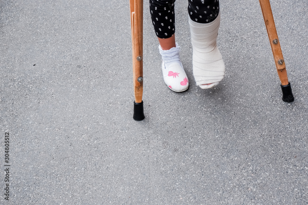 Foto de Little girl with crutches walking outdoor. Back to school.leg