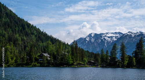 Panoramic view to the Alpine village on lake by Interlaken, Switzerland. Old fishing village with beautiful old wooden house and snow covered Alps mountains on background. Switzerland, Europe.