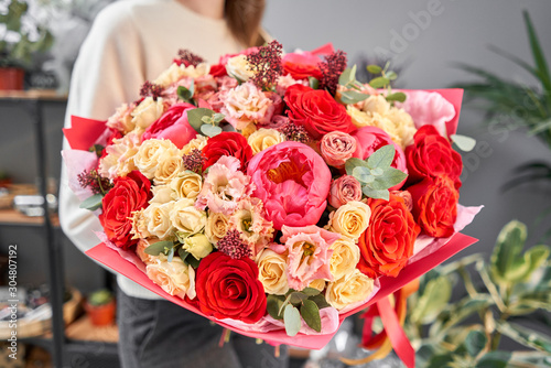 Fototapeta Naklejka Na Ścianę i Meble -  Red tones Beautiful bouquet of mixed flowers in womans hands. the work of the florist at a flower shop. Handsome fresh bouquet. Flowers delivery