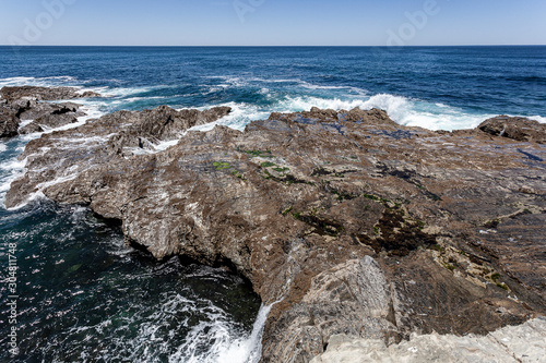 Rebentação das ondas do oceano no rochedo da costa.