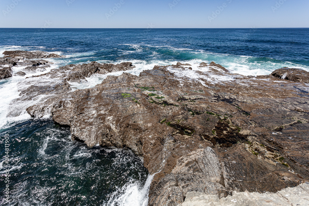 Rebentação das ondas do oceano no rochedo da costa.