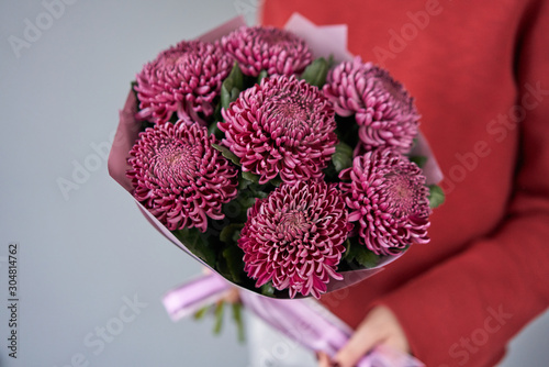 Fototapeta Naklejka Na Ścianę i Meble -  Mono bouquet of chrysanthemum in womans hands. European floral shop. the work of the florist at a flower shop. Delivery fresh cut flower.