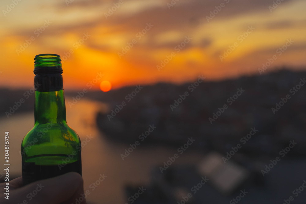 Hand holding bottle on sunset city background. enjoying summer sunset. Alcohol beverage. Hand holding bottle on sunset city background. enjoying summer sunset. Alcohol beverage.