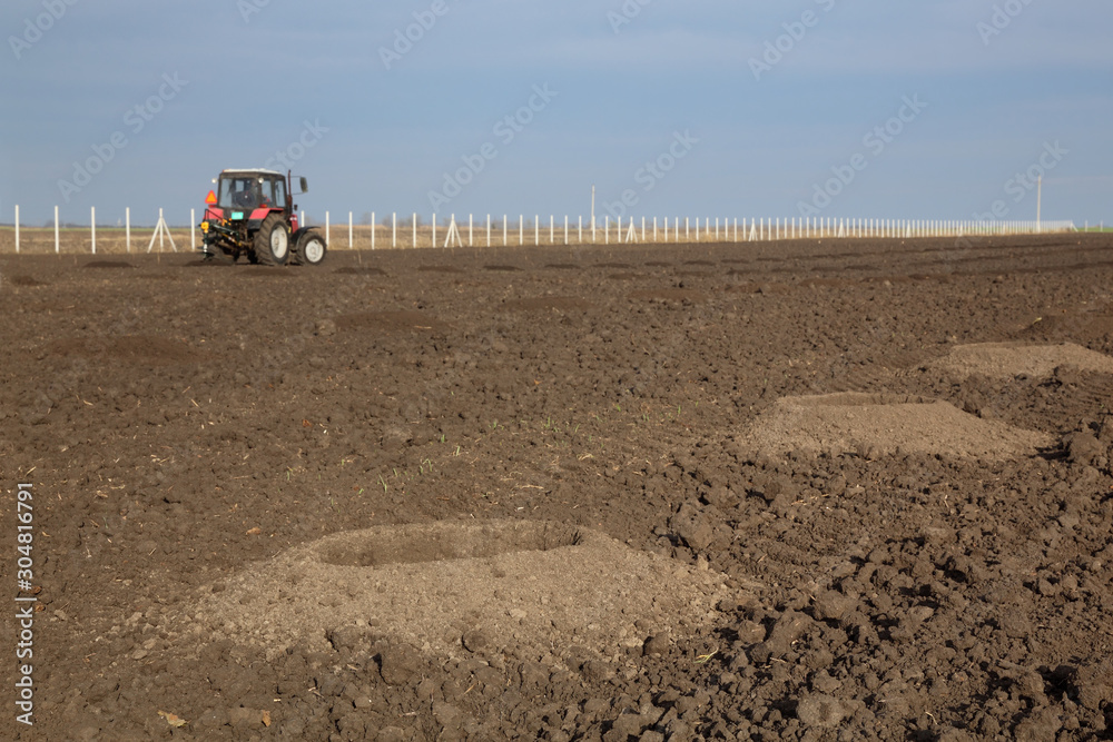 Drilling holes in field, preparing for trees planting Drilling holes in field, preparing for trees planting