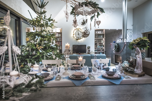 Eleganckie wnętrze nowoczesnego domu przystrojone pięknie na wigilię i święta Bożego Narodzenia, rodzinna wigilia przy świątecznie nakrytym stole photo