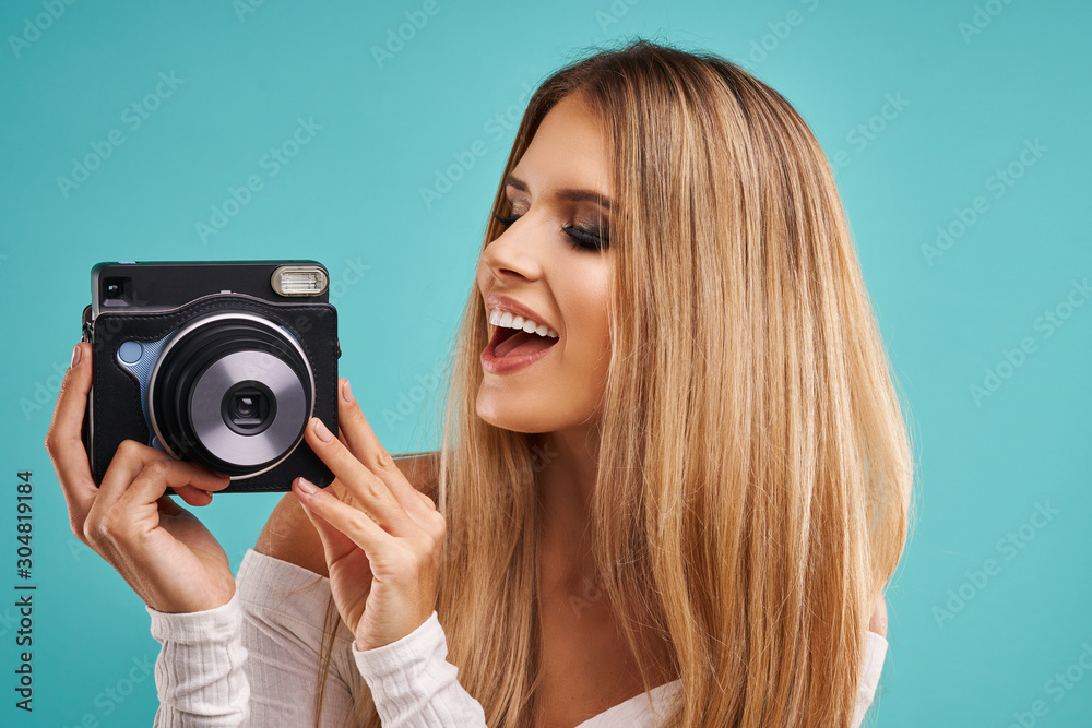 Beautiful adult woman posing over blue background taking instant photos Beautiful adult woman posing over blue background taking instant photos