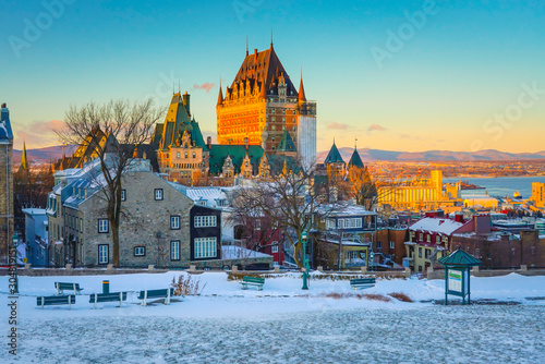 Cityscape View of Quebec City with Chateau Frontenac against St. Lawrence River, Village, Mountains and Vivid Sky in Background at Dusk in Winter