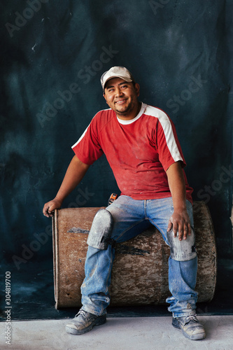 Studio portrait of bricklayer sitting on old barrel in Mexico