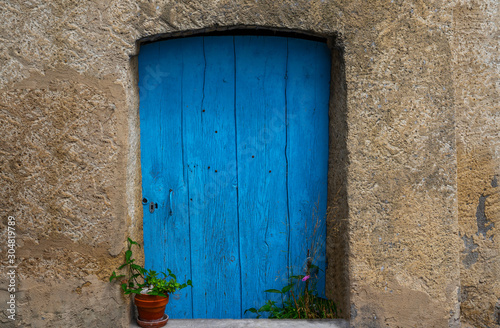 Old building in France. Wall with blue door and flower pot. Building with beautiful old architecture. Old door on old wall.