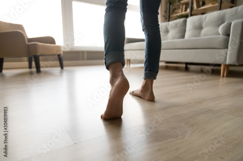 Close up of woman walking barefoot on warm wooden floor