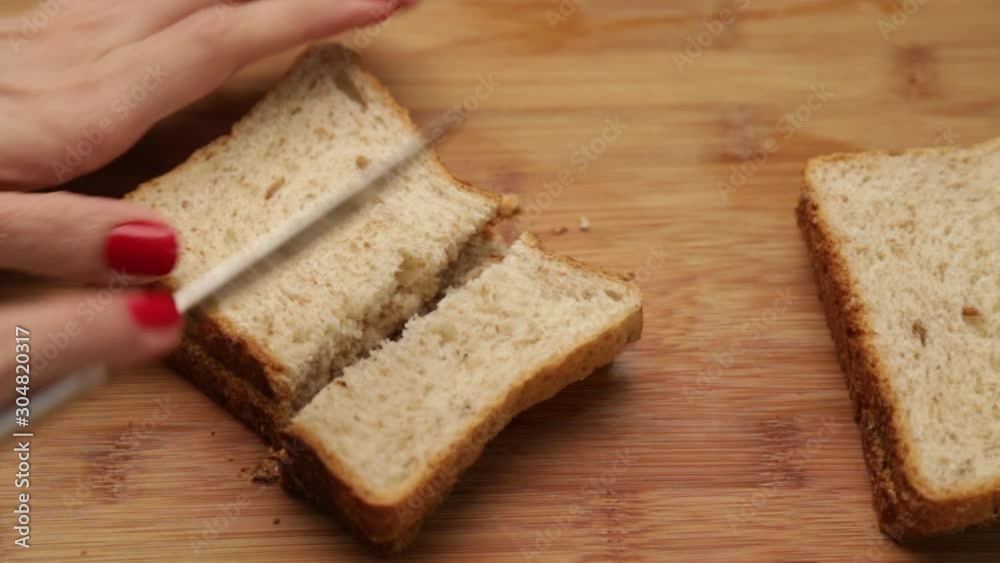 Female hand cutting bread on a wooden board Female hand cutting bread on a wooden board