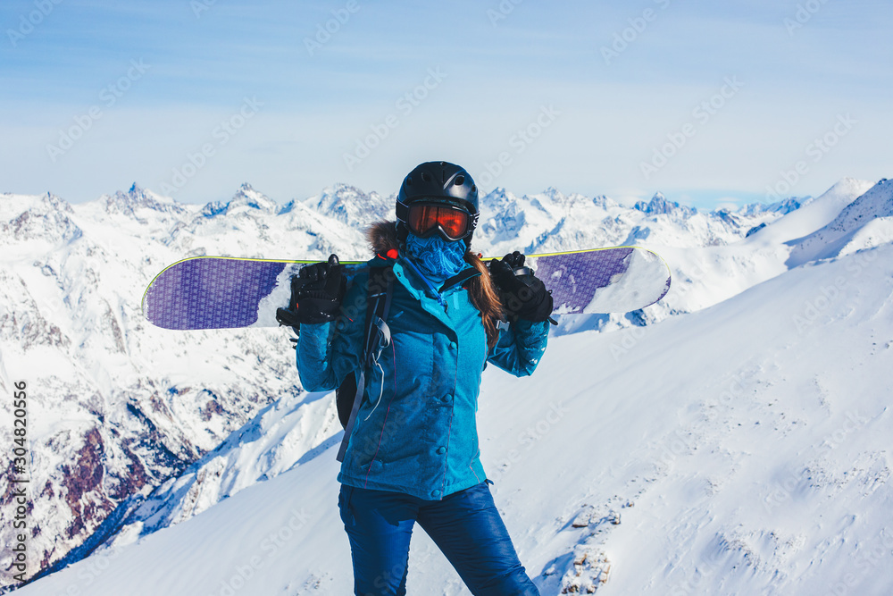 Girl holds a snowboard on her shoulders.