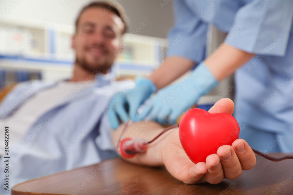 © New Africa - Young man making blood donation in hospital, focus on hand
