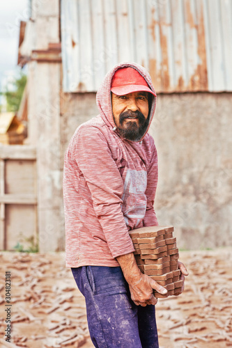 Portrait of man carrying stack of tiles at tile factory