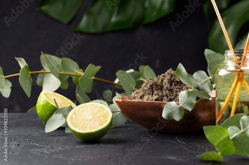 Spa concept. Green tea scrub, aroma oil, eucalyptus and lime on black background. Copy space.