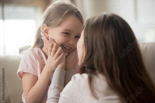 Young mom and smiling little daughter have fun playing