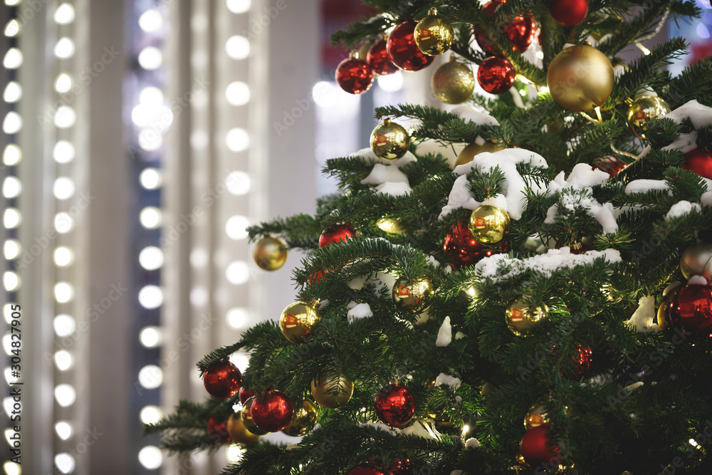 Evergreen spruce with holiday toys and sparkling garlands, covered in snow. Christmas decorations on the evening streets in the center of Moscow. Winter New Year holidays. Selective focus