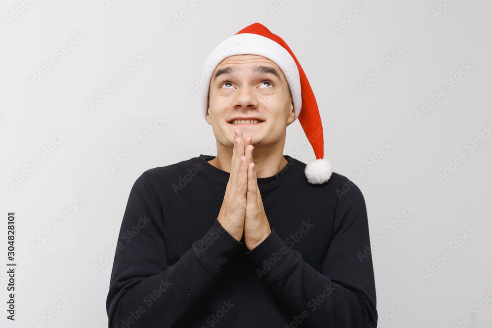 Man being excited about christmas or new year celebration. Happy crazy facial expression isolated on gray background. Boy in a santa hat celebrating. Man being excited about christmas or new year celebration. Happy crazy facial expression isolated on gray background. Boy in a santa hat celebrating.