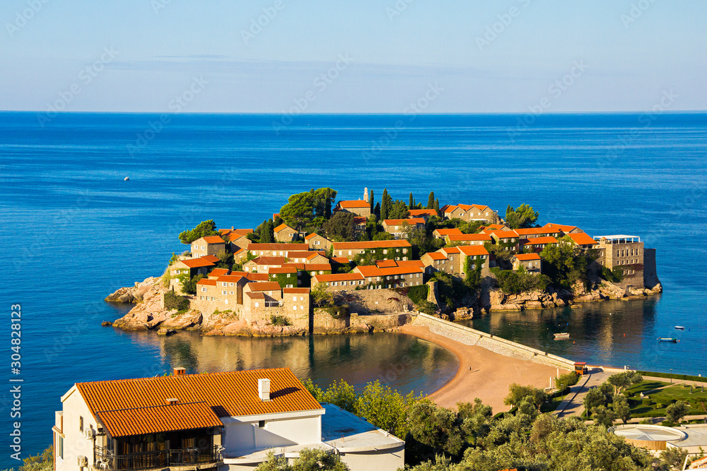 view of one of a beach of Budva town and the island of Sveti Stefan with famous hotel resort in Adriatic sea, Montenegro