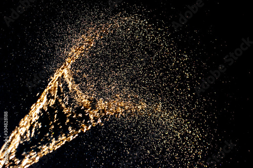 Abstract background. Splashes of yellow water similar to champagne on a dark background. The spray is shiny. Motion blur. Selective shallow focus.