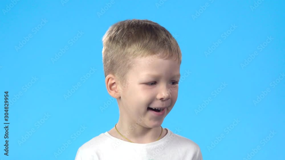 Boy laughing and looking at camera, posing against blue background. Boy laughing and looking at camera, posing against blue background.