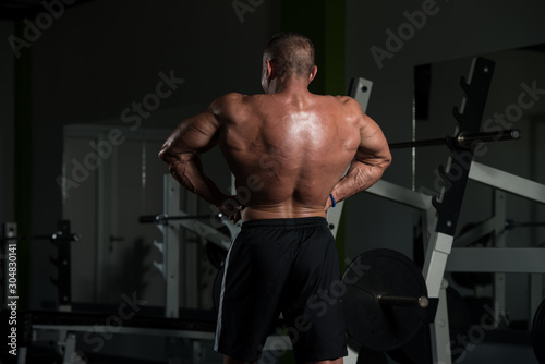 Muscular Mature Man Flexing Muscles In Gym