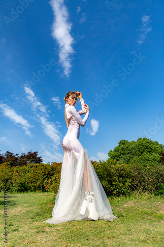 girl in a white long dress on a background of blue sky with white clouds © spaceneospace